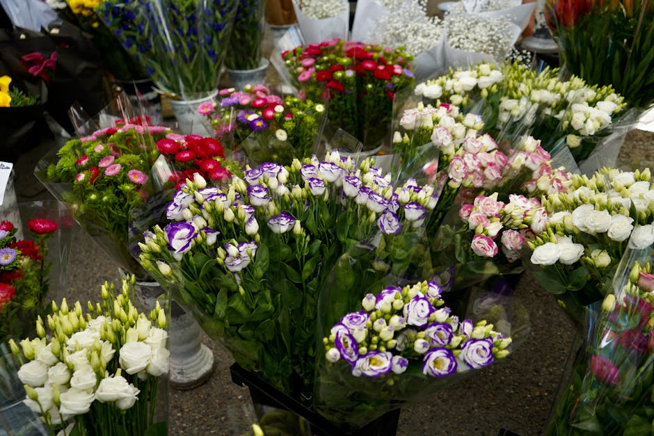 A vibrant display of fresh floral arrangements featuring a variety of flowers such as white lisianthus, purple and white irises, pink and white roses, and small daisy-like blooms in shades of pink and