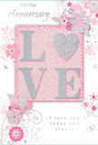 This image shows a beautifully detailed anniversary card that looks as though it was inspired by a romantic stroll through one of Lambeth's hidden gardens. At the heart of the design lies the word LOVE, stamped in generous, raised letters that catch the light with a soft glitter finish. The shimmer is refined rather than bold, casting a silvery, pearlescent glow that calls to mind the gentle sheen on a rose petal chosen for a bouquet in Brixton or West Norwood. The raised texture appears pleasingly tactile, suggesting a subtle ridge beneath the fingertips. Surrounding the central word is a drift of stylised flowers and leaves, swirling in a loose, almost dance-like pattern across the card. The blossoms are depicted in shades of blush pink, creamy white, and soft grey, with delicately drawn outlines and whisper-light shading that gives each flower a sense of quiet volume. Hints of silver detailing add tiny sparks of brightness, like reflections of city lights across the Thames on an anniversary evening. Slender vines, scrolls, and petite curls weave between the petals, while tiny, almost hidden butterflies and flourishes add an extra layer of charm. The background is a soft, powdery pink, subtly varied, as if washed with watered-down paint. Elegant cursive text, including loving anniversary messages, is tucked gracefully into the design, its flowing script echoing the natural curves of stems and leaves. Altogether, the card feels like a pastel bouquet expressed on paper, a gentle, heartfelt way to honour years of shared love and everyday moments in Lambeth, perfect to accompany a delivered arrangement of fresh blooms.